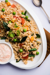 Broken wheat or Daliya Upma, served in a bowl. selective focus