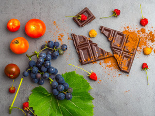 anticancer food, good for cardiovasculas system, fresh ripe grape, dark chocolate, raspberries, tomatoes, apple on concrete background. Food rich in resveratrol, antioxidants