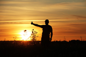 Silhouette of a traveler on a sunset background..Great trip, thumbs up!