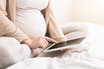 Pregnant woman reading maternity blog on tablet