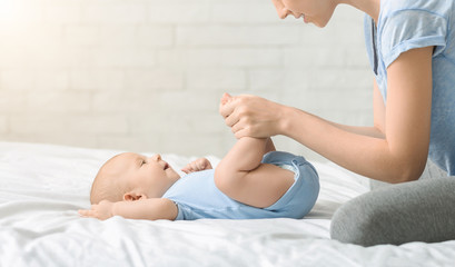 Caring mother making strenghtening exercises with her newborn son