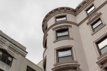 View looking up at rounded corner detail of a painted brick brownstone apartment building,...