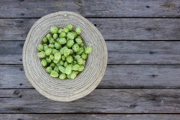 hop cones in straw hat on wooden planks background