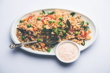 Broken wheat or Daliya Upma, served in a bowl. selective focus