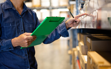 Manager man worker doing stocktaking of product management in cardboard box on shelves in...