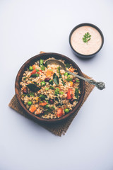 Broken wheat or Daliya Upma, served in a bowl. selective focus