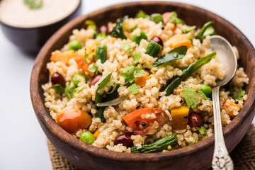 Broken wheat or Daliya Upma, served in a bowl. selective focus