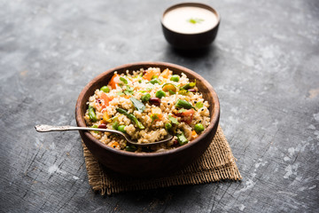 Broken wheat or Daliya Upma, served in a bowl. selective focus