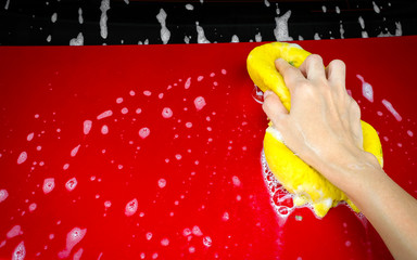 Cleaning automobile with sponge at red car wash
