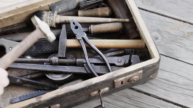 A suitcase with old hand tools closes on a wooden background