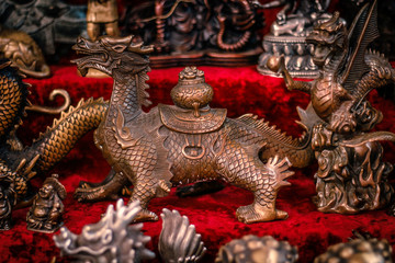 Fototapeta premium Buddhist figurines and masks of mythological characters in gold and bronze on a burgundy with a red background