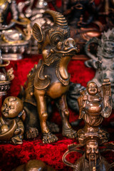 Fototapeta na wymiar Buddhist figurines and masks of mythological characters in gold and bronze on a burgundy with a red background