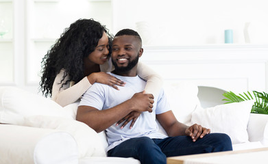 Obraz premium Playful african american woman whispering something to her boyfriend's ear