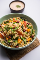 Broken wheat or Daliya Upma, served in a bowl. selective focus