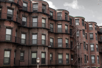 Fototapeta na wymiar Rear view of old brownstone apartment buildings with fire escapes and metal balconies, horizontal aspect
