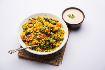Broken wheat or Daliya Upma, served in a bowl. selective focus