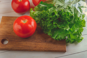 Lettuce and a ripe red tomato on a chopping Board. Fresh fruit