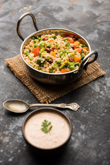 Broken wheat or Daliya Upma, served in a bowl. selective focus