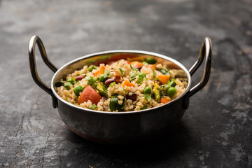 Broken wheat or Daliya Upma, served in a bowl. selective focus