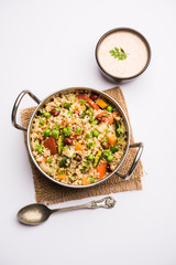 Broken wheat or Daliya Upma, served in a bowl. selective focus