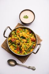 Broken wheat or Daliya Upma, served in a bowl. selective focus