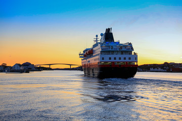 Coastal ships depart from Bronnoysund harbor in sunset, Northern Norway