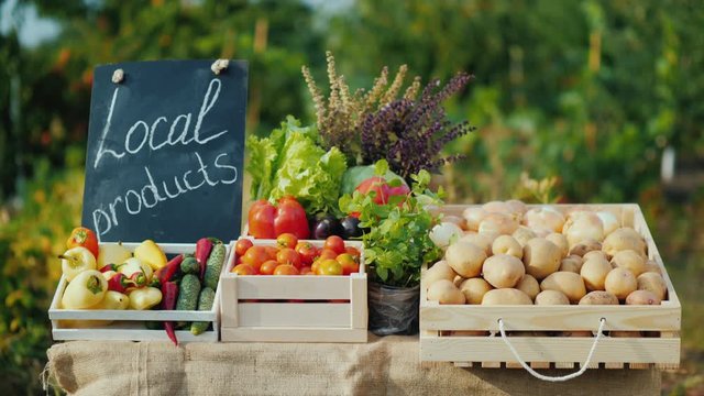 Counter with fresh vegetables and a sign of local products