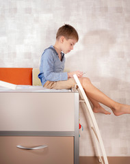 A little boy is playing the tablet in various poses alone at his room