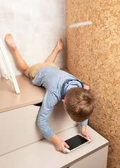 A little boy is playing the tablet in various poses alone at his room