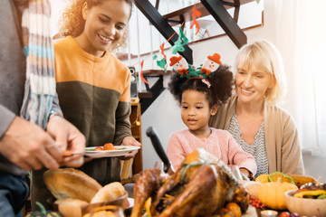 Thanksgiving Celebration Tradition Family Dinner Concept.family having holiday dinner and cutting turkey.Young black adult woman and her daughter happy..