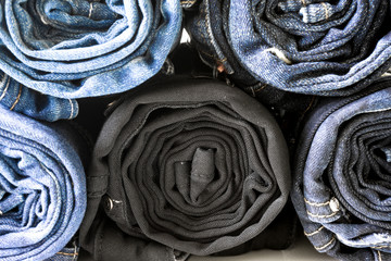 Jeans stacked on white background. Stack of various shades of blue jeans on white background.