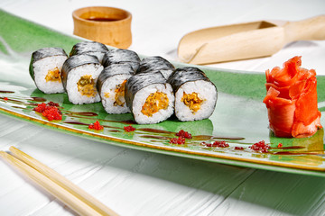Close up view on maki sushi roll with mussel on green plate isolated on white wooden background. japanese sushi food. Seafood