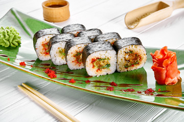 Close up view on maki sushi roll with tuna on green plate isolated on white wooden background. japanese sushi food. Seafood