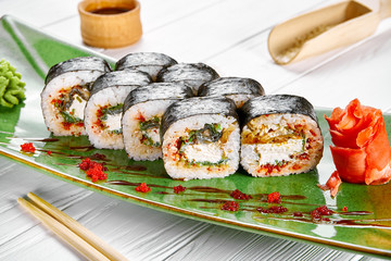 Close up view on maki sushi roll with crab on green plate isolated on white wooden background. japanese sushi food. Seafood