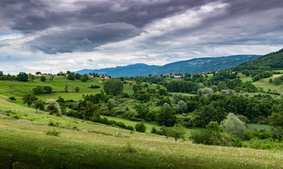 Fototapeta na wymiar View of the mountain landscape,green pastures, trees, forests on the slopes of hills and farmhouses with a cloudy sky in the background.Brens,Haute-Savoie in France.
