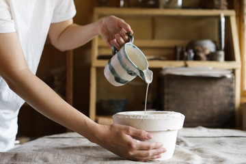 Female hands pour pottery mixture into a mold. Shaped method for making clay dishes. Handwork....
