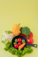 Variety of vegetables and frying pan on a blackboard, top view. Vegan and healthy concept.