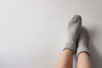 Women wearing grey knitted cozy socks on gray background. Сopyspace for text 