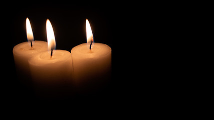 Burning candles on a black background with space to put any text