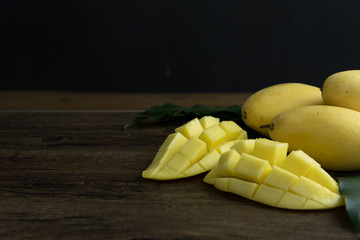 The close up of heap yellow mango and sticky rice setting with coconut milk in the dish on wooden...