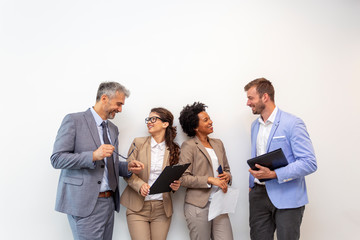 Group of four multiethnic business people standing in front of white wall