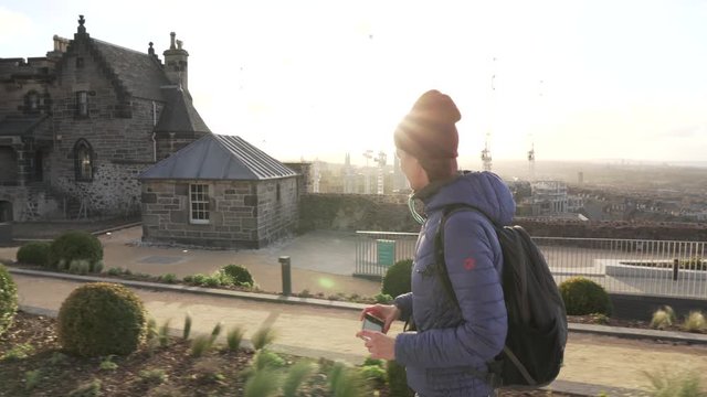 Tracking, follow shot of a girl walking on top or Calton Hill in Edinburgh Scotland during sunset