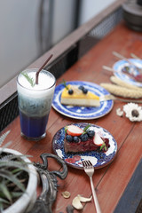 Chocolate moose cake. A melting chocolate moose cake with blueberry and strawberry topping. Abstract blurred of butterfly pea drink latte on the background. Rustic style.