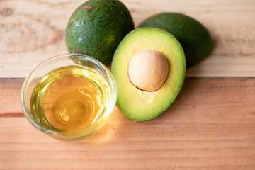 Avocado and avocado oil on a wooden background. Top view. Copy space for your text.