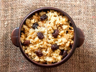 Sweet millet porridge with dark raisins in ceramic rustic bowl