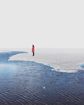 Woman standing on ice at the edge of a lake, South Korea