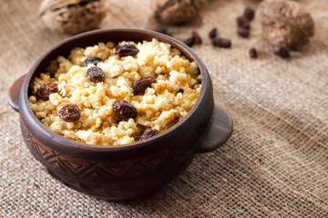 Sweet millet porridge with dark raisins in ceramic rustic bowl