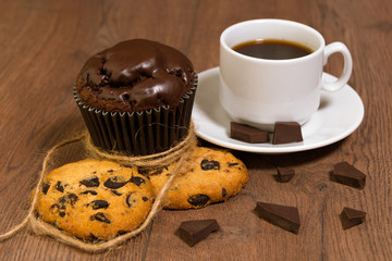 Chocolate muffin on a brown table. A cup of coffee. shortbread.