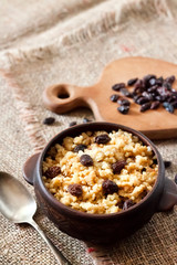 Sweet millet porridge with dark raisins in ceramic rustic bowl