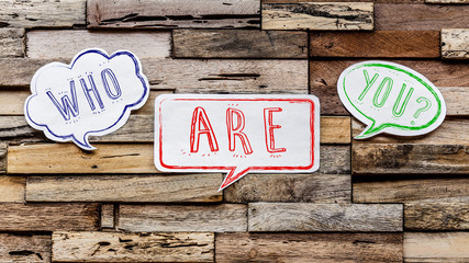 Speech bubbles on wooden background : who are you ?